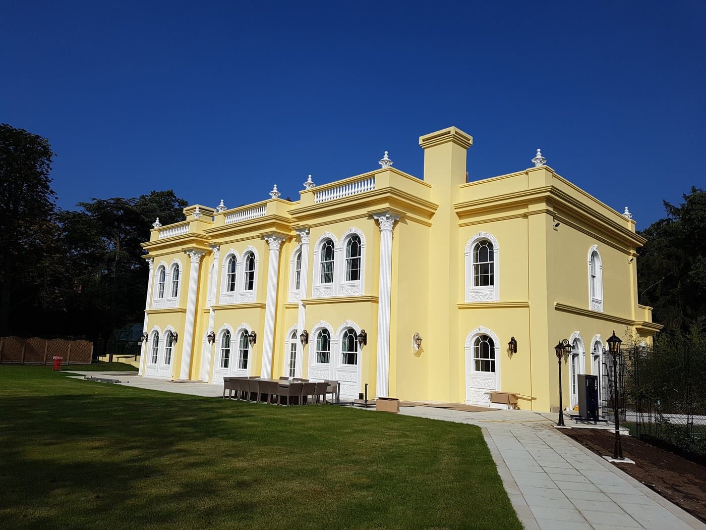 Wide view of the Surrey private residence with Corinthian columns, cornices, arched window surrounds, balustrades and urns.